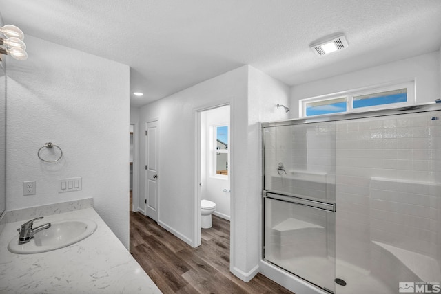 bathroom featuring sink, hardwood / wood-style flooring, toilet, a textured ceiling, and an enclosed shower