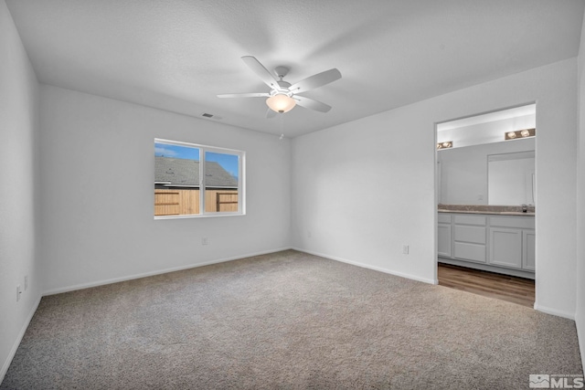 unfurnished bedroom featuring ensuite bath, ceiling fan, sink, and carpet