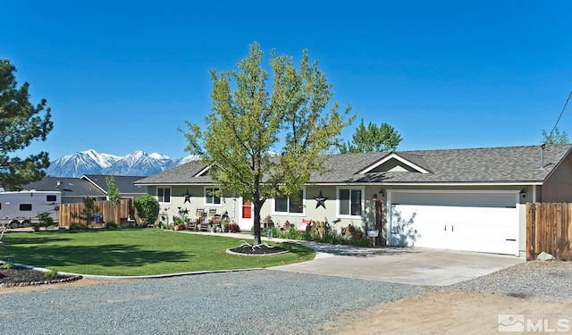 single story home featuring a mountain view, a front lawn, and a garage