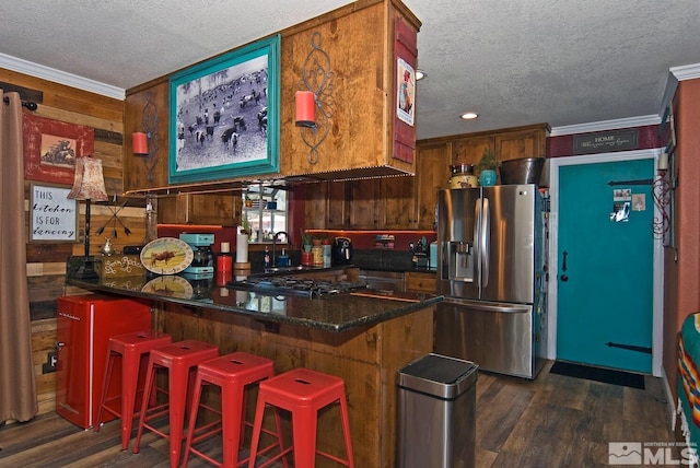 kitchen with a textured ceiling, stainless steel fridge with ice dispenser, kitchen peninsula, and a breakfast bar area