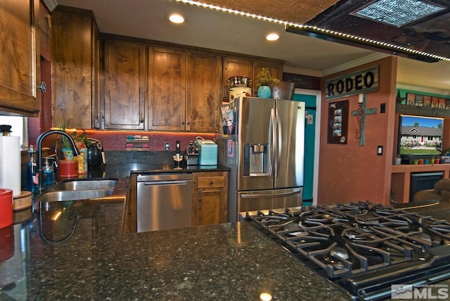 kitchen with dark stone countertops, sink, stainless steel appliances, and ornamental molding