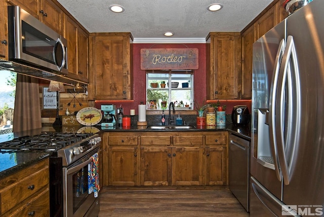 kitchen with appliances with stainless steel finishes, ornamental molding, a textured ceiling, sink, and dark hardwood / wood-style floors