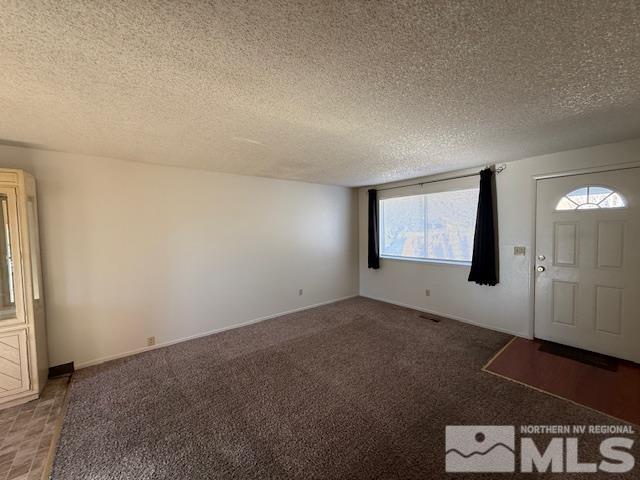 entryway featuring a textured ceiling and dark carpet