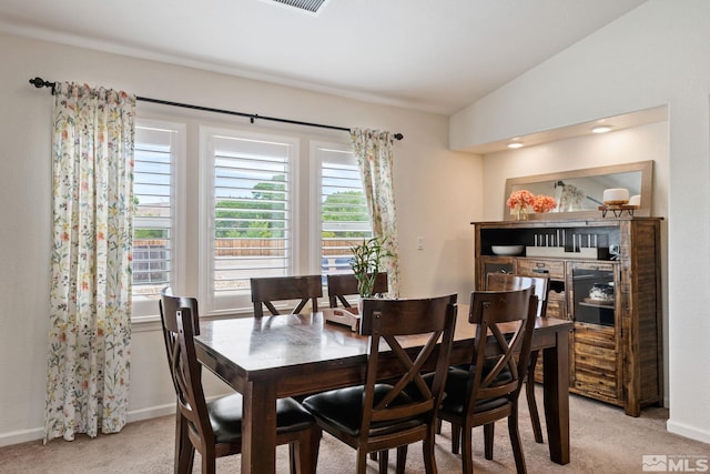 carpeted dining space with vaulted ceiling