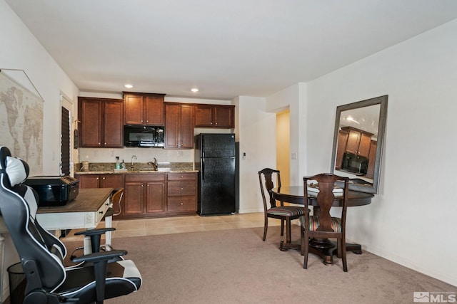 kitchen with sink, light colored carpet, dark stone countertops, and black appliances