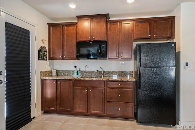 kitchen with light stone countertops, sink, light tile patterned floors, and black appliances