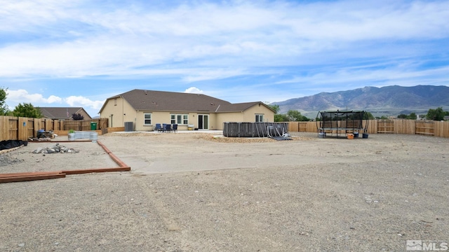 back of house with a mountain view, a trampoline, and a patio area