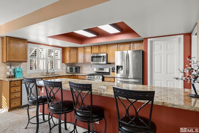 kitchen featuring a kitchen bar, light stone countertops, sink, and appliances with stainless steel finishes