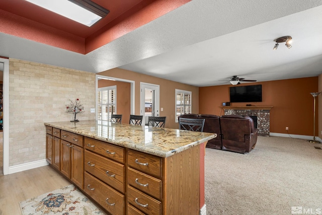 kitchen with a kitchen bar, a tiled fireplace, a wealth of natural light, and light stone countertops