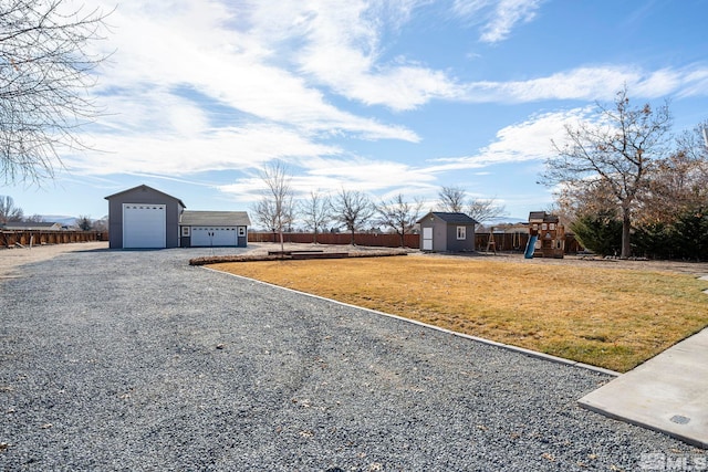 view of yard featuring a playground, a garage, and a storage shed