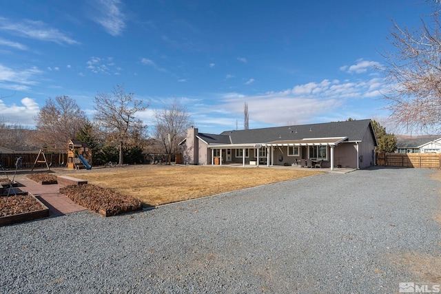 ranch-style home with a playground and a front lawn