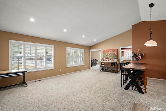 carpeted dining room with lofted ceiling