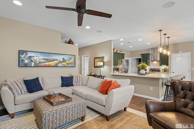 living room featuring ceiling fan with notable chandelier and light hardwood / wood-style flooring