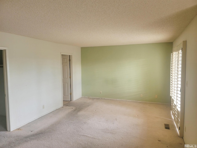 unfurnished bedroom with light colored carpet and a textured ceiling