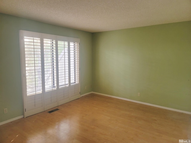 empty room featuring a textured ceiling and light wood-type flooring