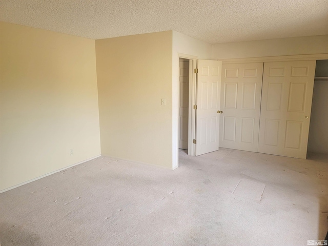 unfurnished bedroom with a textured ceiling, light carpet, and a closet