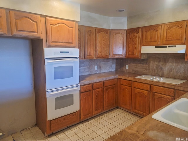 kitchen featuring backsplash, sink, and white appliances