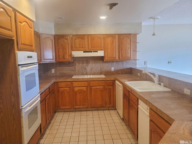 kitchen featuring decorative backsplash, white appliances, sink, light tile patterned floors, and decorative light fixtures