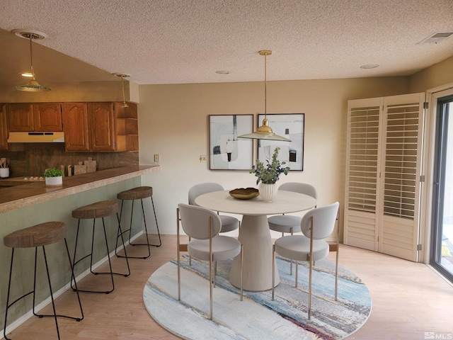 dining area with light hardwood / wood-style floors and a textured ceiling