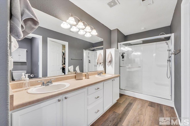 bathroom with vanity, toilet, wood-type flooring, and a shower with shower door