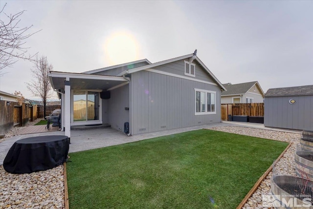 back of property with a storage unit, a patio area, and a lawn