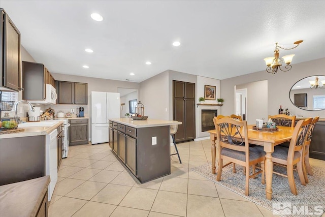 kitchen featuring hanging light fixtures, a kitchen island, a chandelier, white appliances, and light tile patterned floors