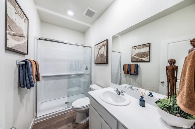 bathroom with vanity, toilet, wood-type flooring, and a shower with door