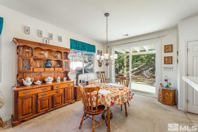 dining area with light carpet and an inviting chandelier