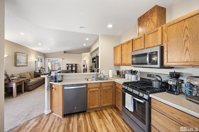 kitchen featuring kitchen peninsula, light wood-type flooring, stainless steel appliances, sink, and lofted ceiling