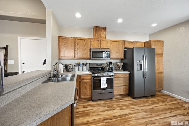 kitchen with appliances with stainless steel finishes, light wood-type flooring, and sink