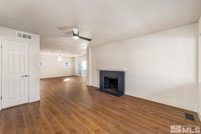 unfurnished living room featuring a textured ceiling, ceiling fan, and dark wood-type flooring