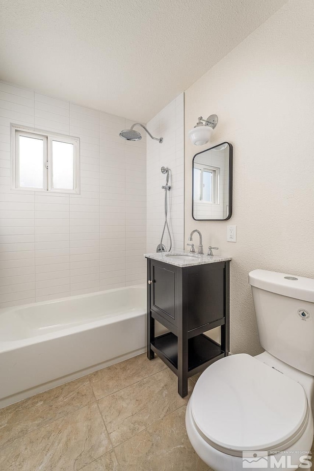 full bathroom featuring a textured ceiling, vanity, tiled shower / bath combo, and toilet