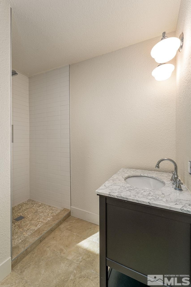 bathroom featuring vanity, a textured ceiling, and tiled shower