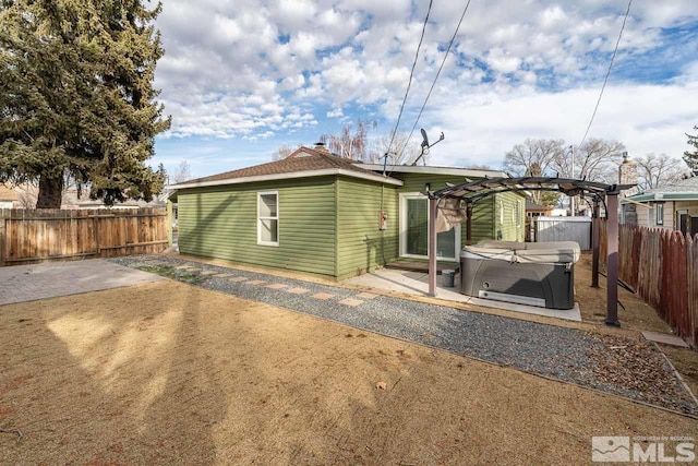 rear view of property with a patio, a pergola, and a hot tub