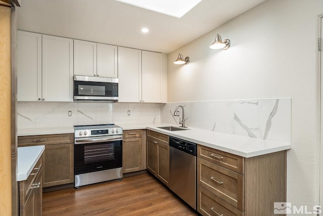 kitchen featuring decorative backsplash, sink, white cabinets, and appliances with stainless steel finishes