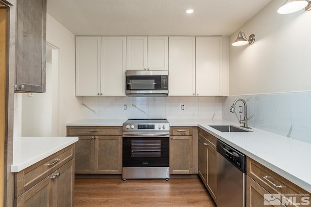 kitchen with backsplash, white cabinetry, sink, and stainless steel appliances