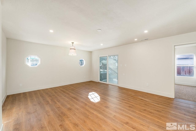 unfurnished room with a textured ceiling and light hardwood / wood-style floors