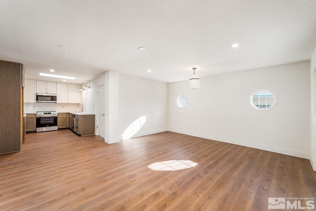 unfurnished living room featuring sink and light hardwood / wood-style floors