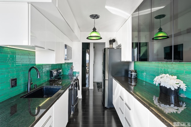 kitchen featuring dark stone counters, sink, black / electric stove, decorative light fixtures, and white cabinetry