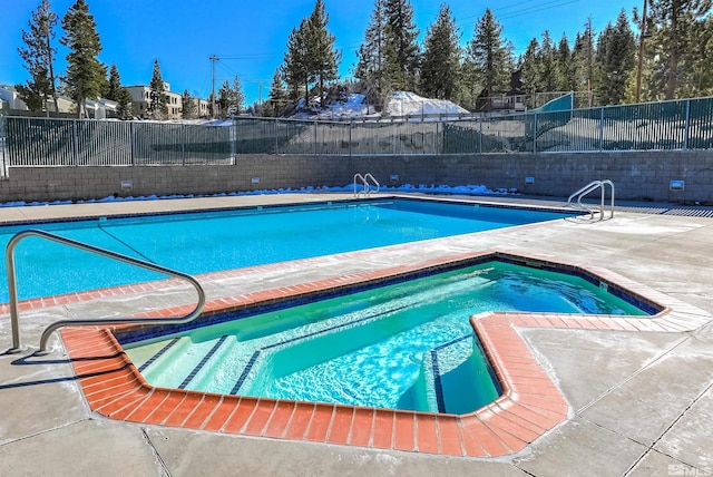 view of swimming pool with an in ground hot tub