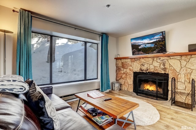 living room with a stone fireplace, hardwood / wood-style floors, and a baseboard heating unit