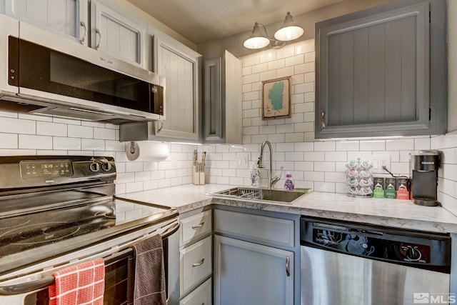 kitchen with backsplash, gray cabinetry, sink, and appliances with stainless steel finishes