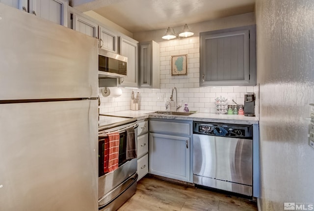 kitchen with gray cabinets, sink, appliances with stainless steel finishes, and tasteful backsplash