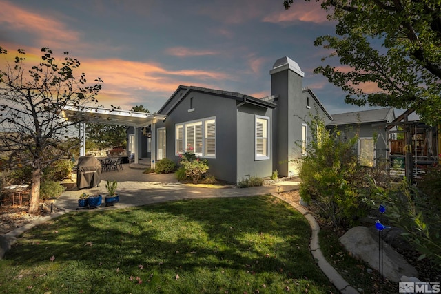 property exterior at dusk featuring a pergola, a patio area, and a lawn