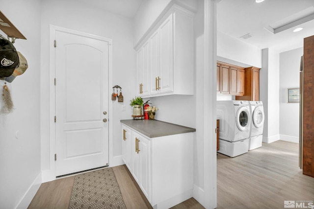 washroom with cabinets, separate washer and dryer, and light wood-type flooring