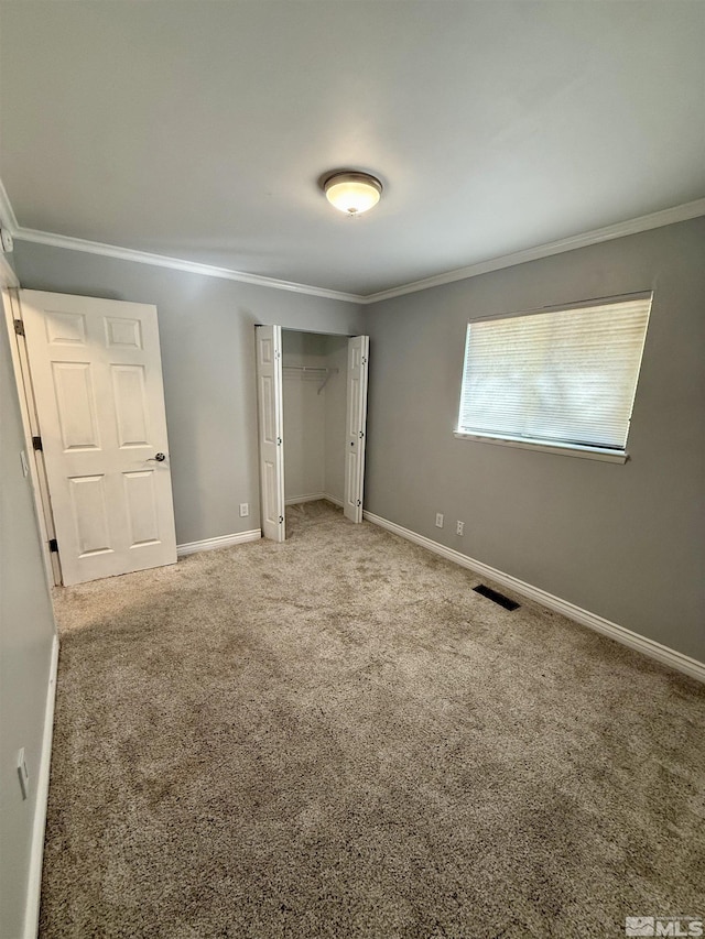 unfurnished bedroom with a closet, crown molding, and carpet