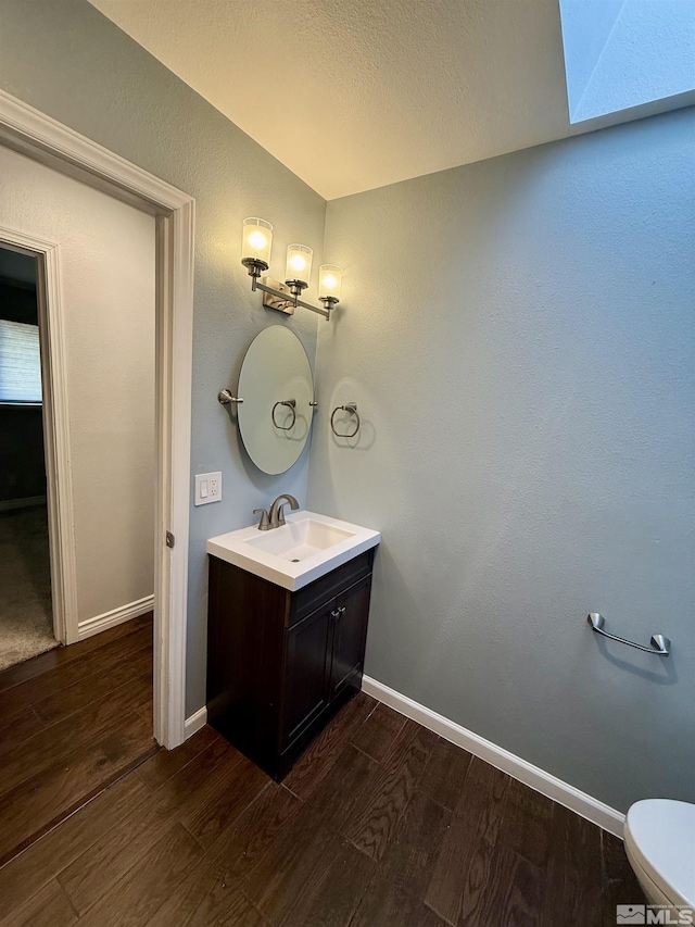 bathroom with hardwood / wood-style floors, vanity, and toilet