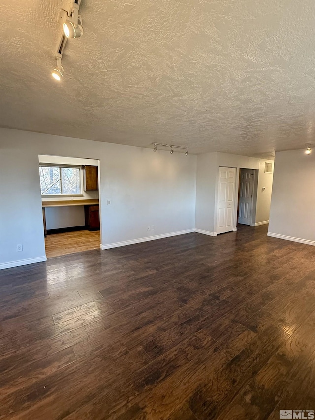 spare room with track lighting, a textured ceiling, and dark hardwood / wood-style floors