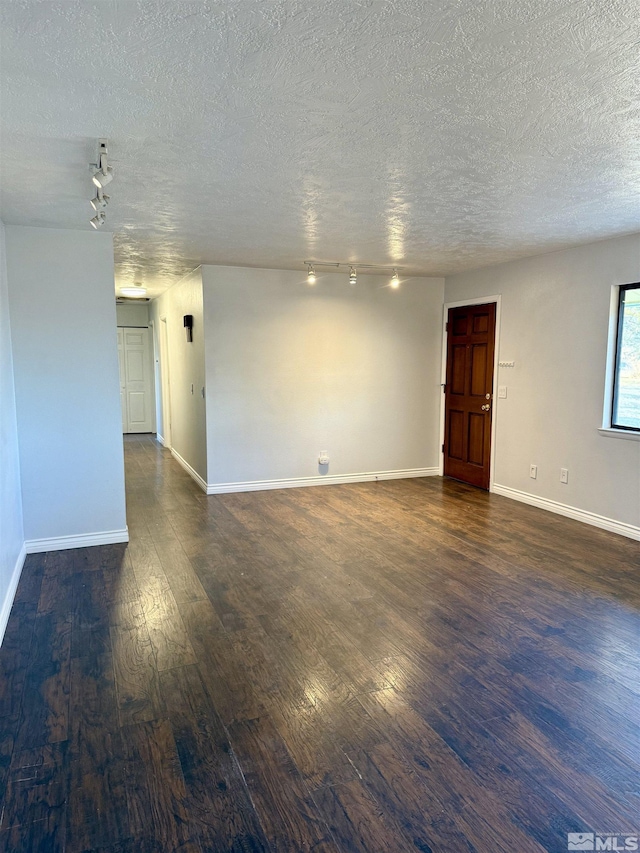 empty room with dark hardwood / wood-style flooring and a textured ceiling