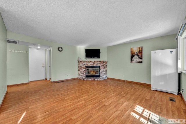 unfurnished living room with a textured ceiling, a fireplace, and light hardwood / wood-style flooring